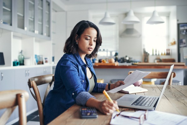 Woman at table working on a laptop and calculator